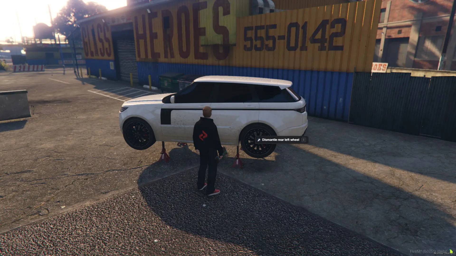 A white SUV up on four jack stands, drill in hand, with the rear left wheel prompt showing